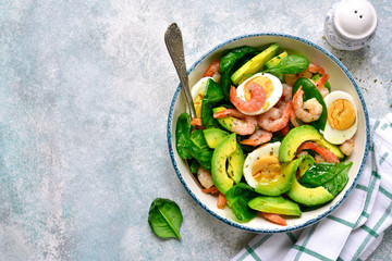 Avocado salad with baby spinach, shrimps and boiled eggs.Top view with copy space.