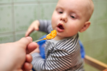 Parent feeds baby a pumpkin with a spoon