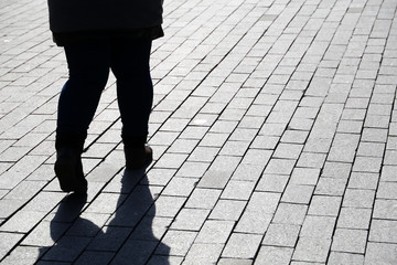 Silhouette of fat woman walking down the street, black shadow on pavement. Thick legs in jeans, concept of overweight, diet, loneliness, dramatic life story