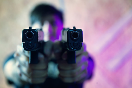man pointing a gun at the target on dark background selective focus on front gun