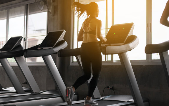 Sport asian woman running on treadmills doing cardio training,Cross fit body and muscular in the gym,Toned image,Back views