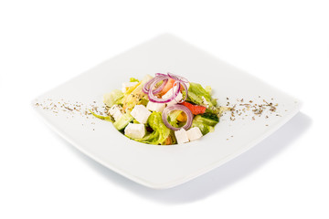 Salad with cucumber, tomato, cheese, onions and herbs on a white background. Isolate