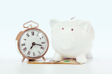 Piggy bank with clock on the heap of money.