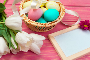 easter, holidays, tradition and object concept - close up of colored eggs and tulip flowers over wooden boards background