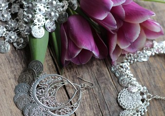 Indian decorations for dancing: earrings, necklace,  belt  for Punjabi folk dances and three purple tulips. Wooden background.