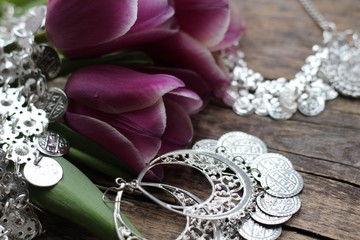 Indian decorations for dancing: earrings, necklace,  belt  for Punjabi folk dances and three purple tulips. Wooden background.