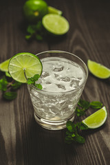 Glass of water with lime, ice and mint. Isolated on wooden background.