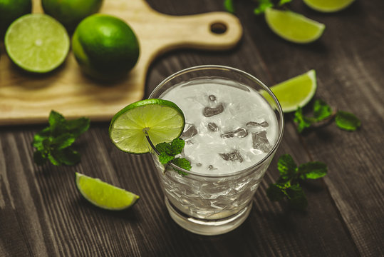 Glass of water with lime, ice and mint. Isolated on wooden background.