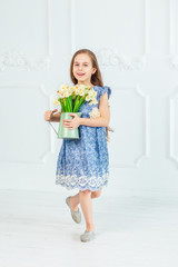 Portrait of a beautiful blue-eyed girl, a little girl among spring flowers in a bright room.
