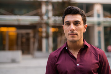 Obraz premium Young handsome Hispanic businessman thinking outside the office building
