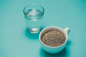 Glass of water and healthy chia seeds in a spoon. Text space.