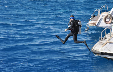 Hurghada, Egypt, man jumping in water for diving to coral reef, prepare for diving, Red sea