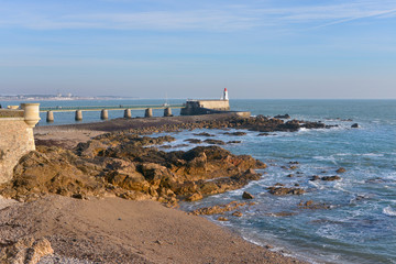 Fototapeta na wymiar Rocky coastline and lighthouse at Les Sables d'Olonne, commune in the Vendée department in the Pays de la Loire region in western France