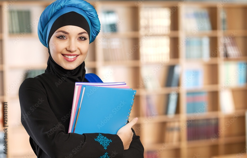 Wall mural Beautiful Young Muslim Woman with notebooks on  background