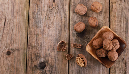 walnuts on a rustic wooden table - close up - walnuts broken up and closed