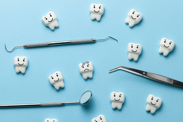 White tooth with caries on blue background  and dentist tools mirror, hook.
