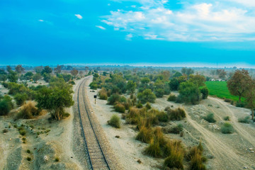old railway line in a forest with cloudy sky.