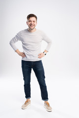 full body picture of a smiling casual man standing on white background.