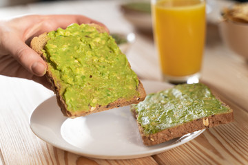 toast bread with guacamole on wooden cutting board - close up