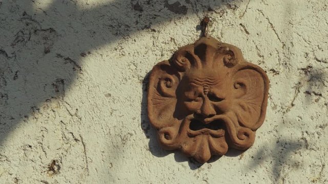 dolly shot of a terracotta mask on the wall
