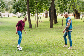 multicultural friends playing football on green grass in park