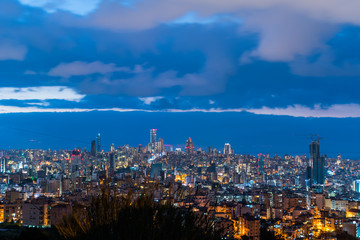 Naklejka premium To jest uchwycenie zachodu słońca w stolicy Libanu w Bejrucie z chłodnym niebieskim odcieniem, a na pierwszym planie widać centrum Bejrutu z piękną chmurą w tle