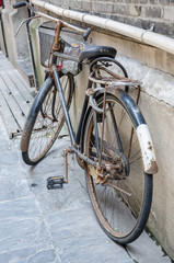 An old bike resting up against a wall.