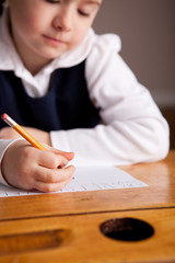 Little Girl Writing While Sitting in Old School Desk - Education - Closeup