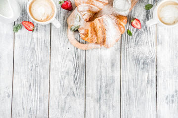 Breakfast concept with coffee cup, croissants, cream and fresh berries. On a light wooden background, top view, copy space
