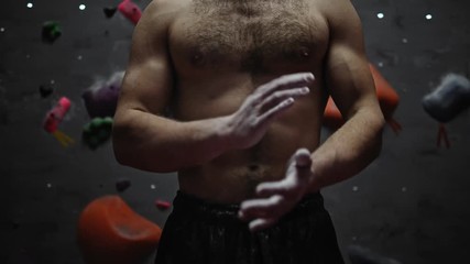 Athletic man applying magnesium before climb in a bouldering gym