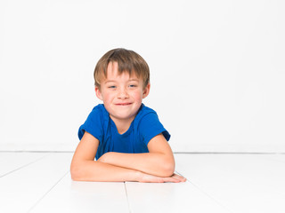 cool and cute and beautiful six year old boy with red trousers and blue shirt on white floor