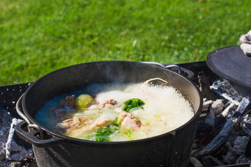 Shurpa soup in a large cast-iron cauldron outdoor. Summer food for hike.