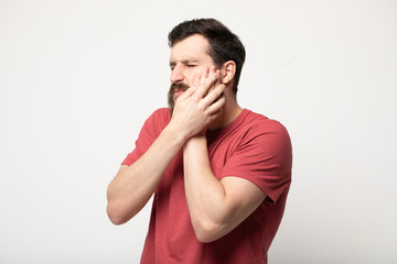 Young man suffering from toothache on grey background 