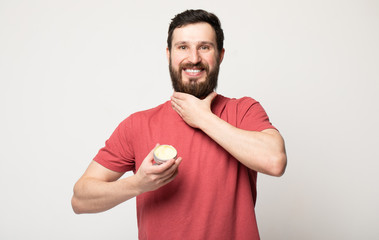 Close-up image of handsome bearded man holding beard balm. 