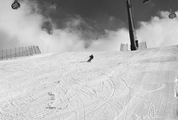 Skier downhill on snowy ski slope at sun winter day