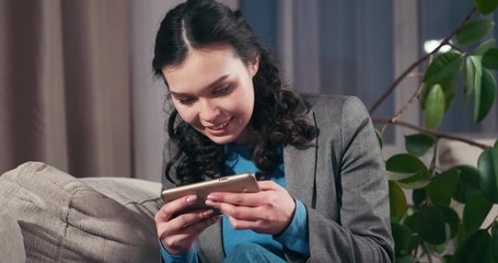 Excited businesswoman playing online game on mobile phone at home
