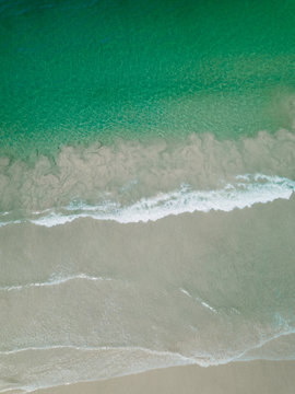 Luftbild Dronenaufnahme von Wellen und Sandstrand mit Steinen 
