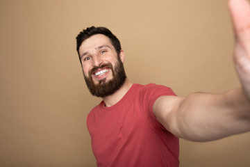 Obraz premium Close up photo of beautiful amazing bearded brunet he him his handsome hold telephone in arms make take selfie wear casual checkered plaid t-shirt outfit isolated on beige background