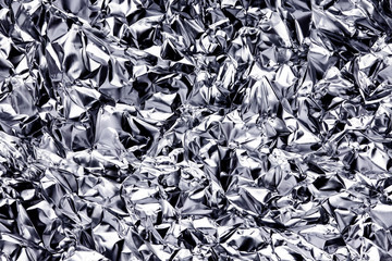 Silver crumpled metal foil texture. Metal glossy surface background. Futuristic backdrop for graphic design.