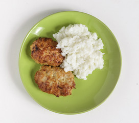 Cutlets and boiled rice on a plate on a white background.