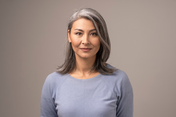 Beautiful Mongolian Woman with Gray Hair on a Gray Background.