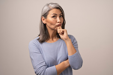 Adult Mongolian Woman with Gray Hair on a Gray Background.