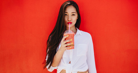 Young asian woman drinking juice