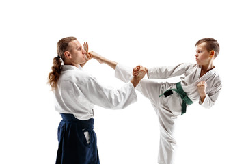 Man and teen boy fighting at Aikido training in martial arts school. Healthy lifestyle and sports concept. Fightrers in white kimono on white background. Karate men with concentrated faces in uniform.