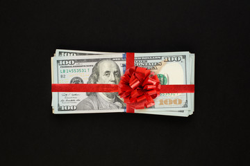 Money us dollars cash gift with red ribbon on black background. American Dollar 100 banknote gift profit concept