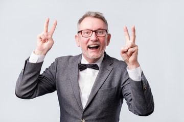 happy senior man making the victory or peace hand sign