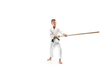 Teen boy fighting with wooden sword at Aikido training in martial arts school. Healthy lifestyle and sports concept. Fightrer in white kimono on white background. Karate man in uniform.