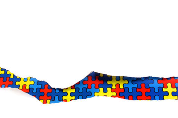 torn white paper on multicolored puzzle background. Cocept for autism awareness day. Break barriers together for autism.
