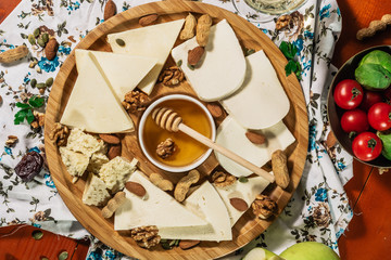 Tasting cheese dish with herbs and snacks on old light wooden table. Food for wine and romantic, cheese delicatessen. Menu design horizontal. Top view.