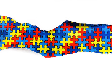 torn white paper on multicolored puzzle background. Cocept for autism awareness day. Break barriers...
